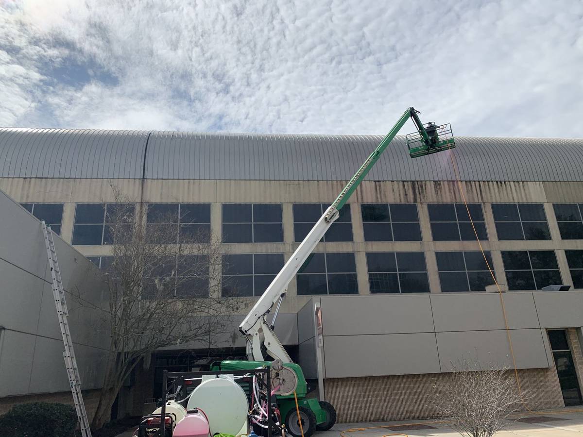 Pressure washing a commercial building exterior with a boom lift near Jacksonville, FL