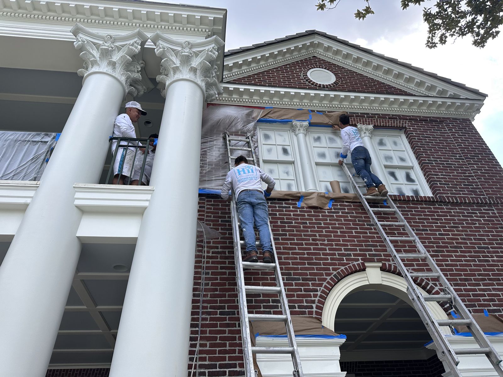 Hospitality Improvements Inc. crew painting columns and window trim on a Jacksonville-area home