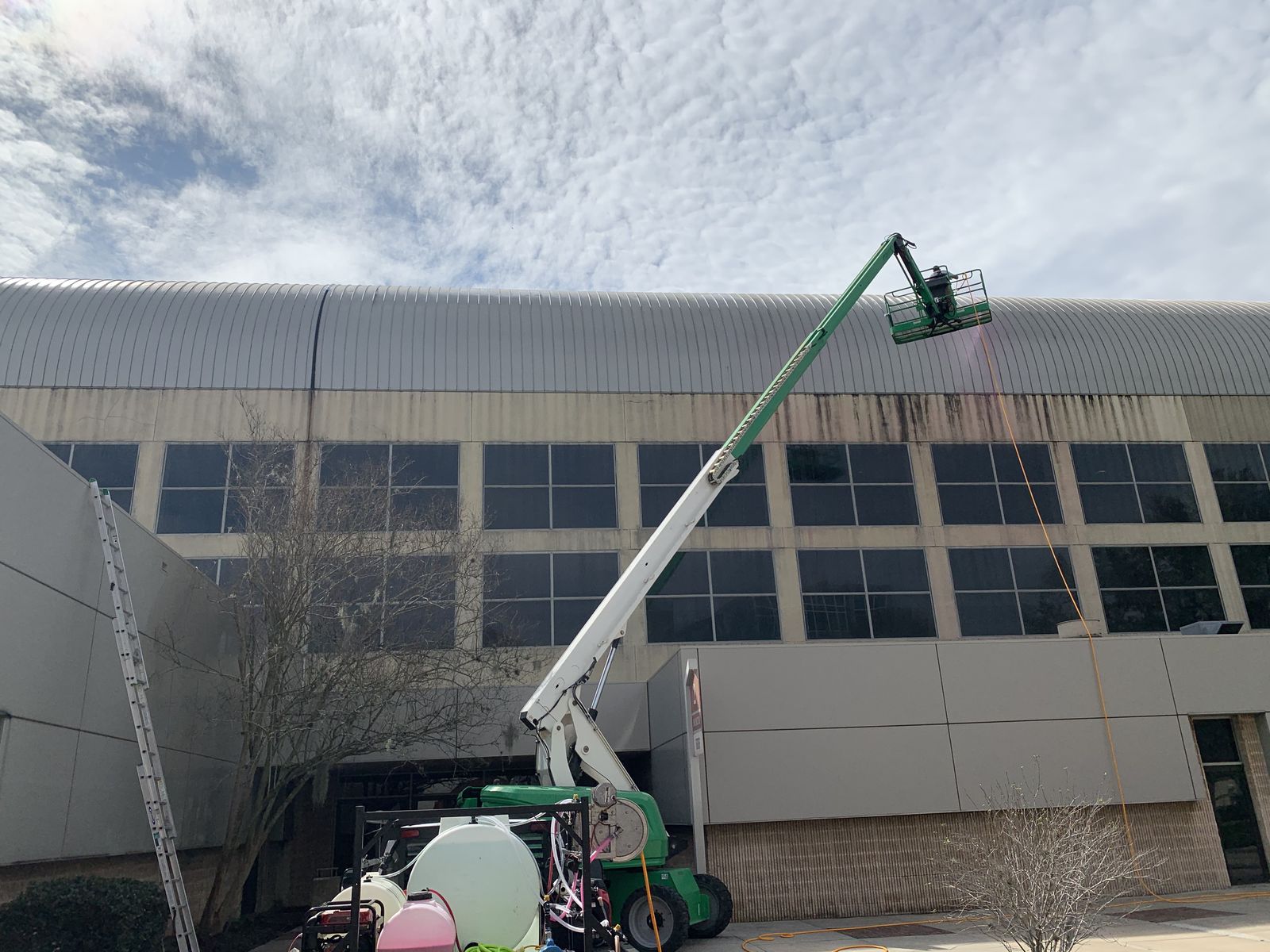 Pressure washing a commercial building exterior with a boom lift near Jacksonville, FL